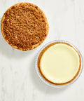 Two mini pies, one with a crumbly crust and the other with a smooth filling, on a marble surface.