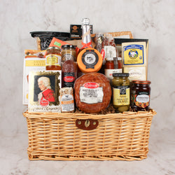 A grand gourmet gift basket with a very large selection of meat and cheese, a mini ham, pasta and sauce, snacks, chocolate and more. Includes a bottle of Cuvée Rosé  sparkling wine wrapped in a picnic basket. 
