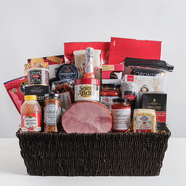 A grand gourmet gift basket with a very large selection of meat and cheese, a mini ham, pasta and sauce, snacks, chocolate and more. Includes a bottle of 13th Street Cuvée Rosé sparkling wine wrapped in large basket.