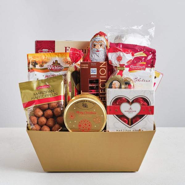 A gold box filled with German Christmas sweets and chocolates such as stollen, marzipan, spiced cookies and a chocolate Santa