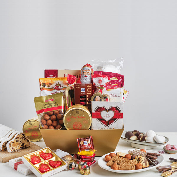 A gold box filled with German Christmas sweets and chocolates such as stollen, marzipan, spiced cookies and a chocolate Santa