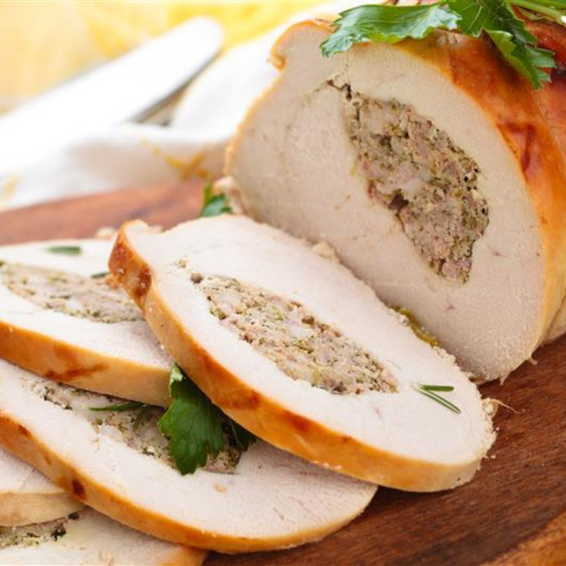 Whole roasted turkey breast with 5 slices cut showing the centre filled with stuffing.