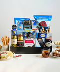 Assorted snacks in a black box with a sampling of items from the box in bowls and plates.