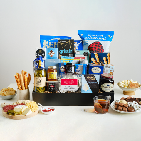 Assorted snacks in a black box with a sampling of items from the box in bowls and plates.