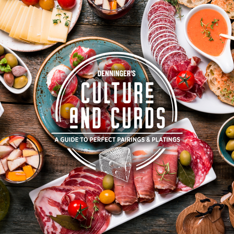 A styled food spread on a rustic wooden table featuring sliced cured meats, cheese wedges, olives, crackers, and dipping sauces, with a large central title reading 'Denninger's Culture and Curds: A Guide to Perfect Pairings & Plating.' This is not a clean isolated product shot; it shows the product in a real tabletop environment with food props, so subject_type is Lifestyle rather than Product/Packaging.
