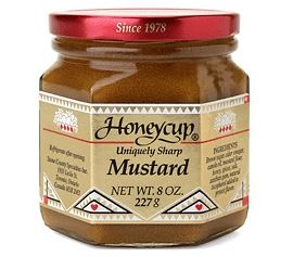 A jar of Honeycup Mustard Original with a red lid and a label showing the brand and product name, net weight 8 oz.