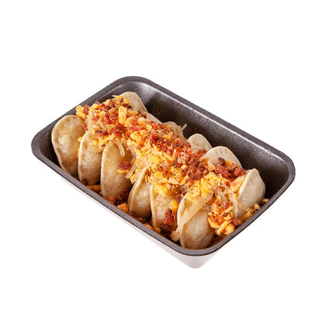 Cooked pierogies with bacon, onion and sour cream in a black container.